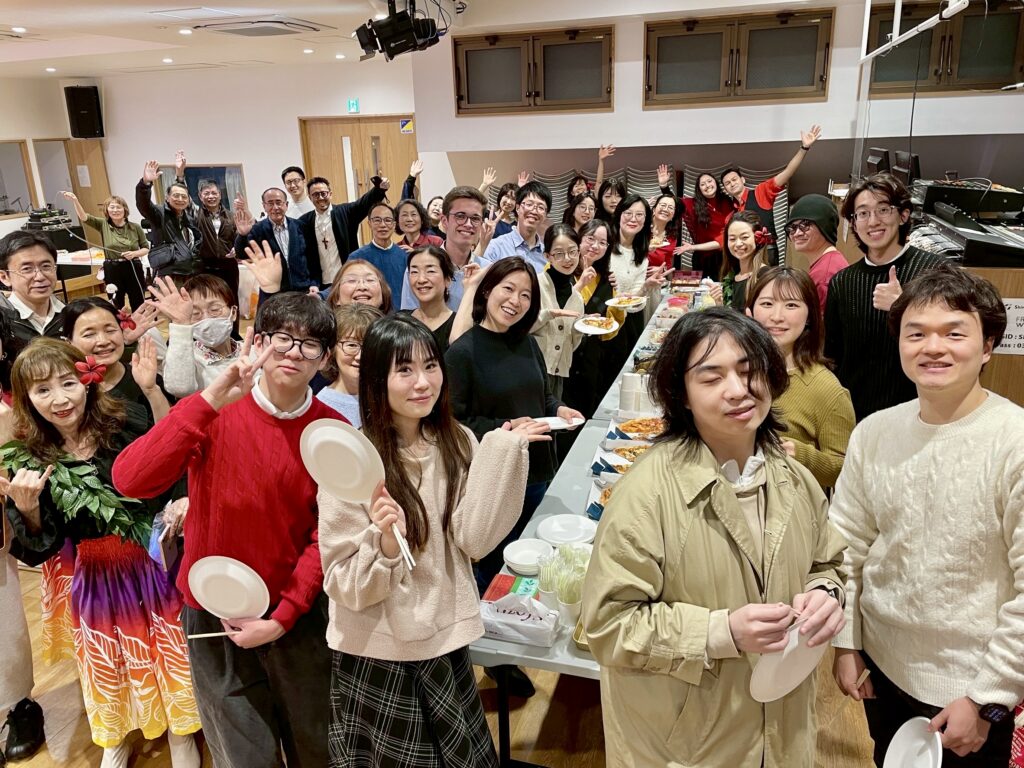 Shalom International church family smiling and waving during Christmas fellowship.